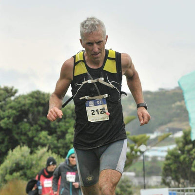 Man running in a race with a number on his chest, surrounded by trees and cones.