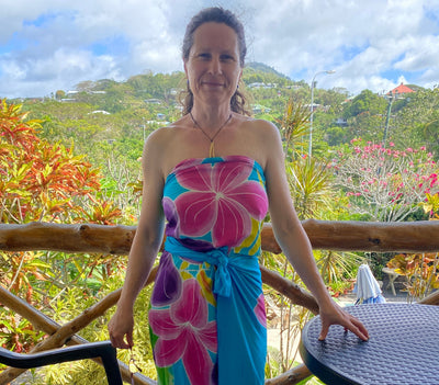 Woman in a colorful floral dress standing on a balcony with a scenic background